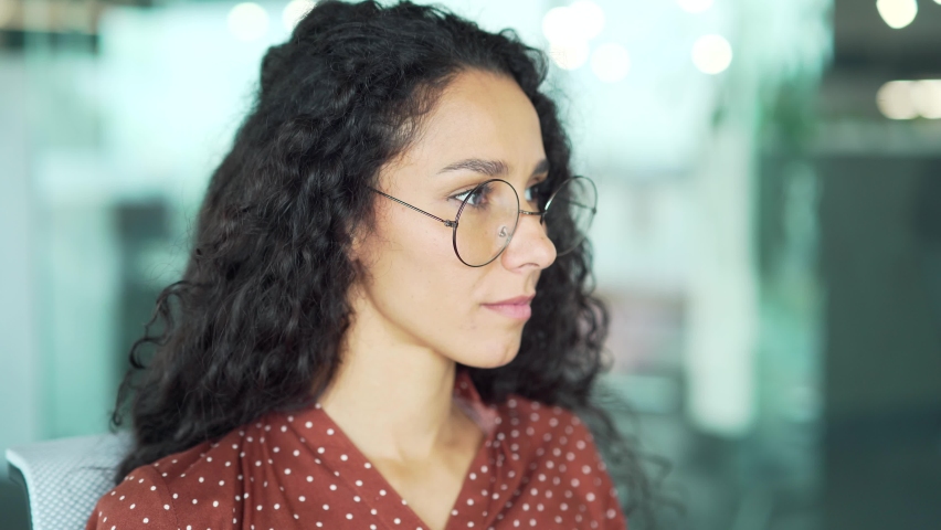 Portrait of a pleasant young female employee wearing glasses looking at camera smiling at workplace in the office Cute business woman or university student creative designer or specialist indoors Royalty-Free Stock Footage #1097478149