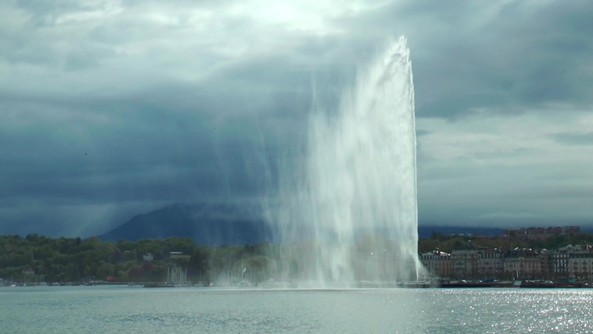 Switzerland. Beautiful summer evening landscape of Lake Geneva with picturesque shores and pleasure ship against Alpine mountains. Geneva harbour with a famous fountain.