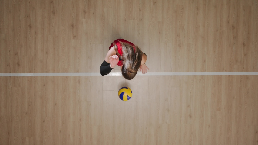 Top view of a young woman hitting ball on wooden floor, tossing and hitting the ball in jump. Female athlete works out skills of serving ball before competition. Royalty-Free Stock Footage #1097484195