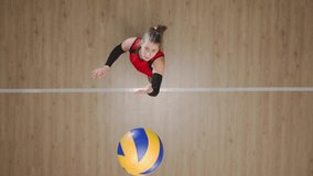 Top view of a young woman hitting ball on wooden floor, tossing and hitting the ball in jump. Female athlete works out skills of serving ball before competition. - Powered by Shutterstock - Get 15% off with code: PIKWIZARD15