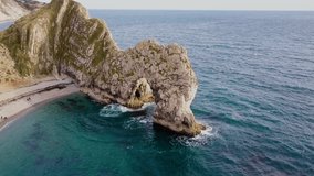 Drone video of Durdle Door arch and beach with people on the beach