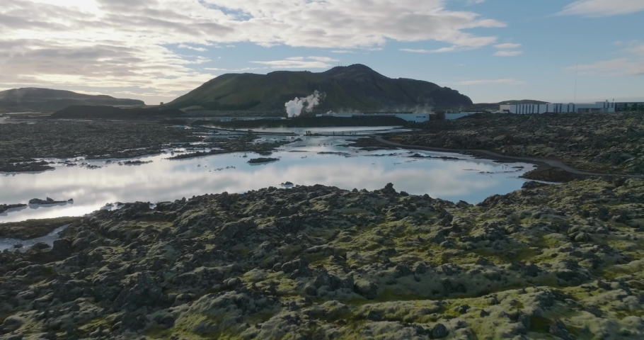 aerial footage of blue water of blue lagoon with sky and rocks reflection in water