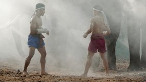Two Young males wearing Thai tradition short, head and hands wrapped in twisted hemp rope and showing beautiful fighting art of Muay Thai, Blurred elephants and spreading white mist in background - Powered by Shutterstock - Get 15% off with code: PIKWIZARD15