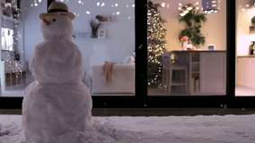 fluffy snow flying on evening patio with snowman and modern aparment during Christmas holidays at the background - Powered by Shutterstock - Get 15% off with code: PIKWIZARD15