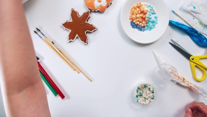 Women's hands decorate a Christmas gingerbread snowflake shape on the kitchen table close-up timelapse | Shutterstock HD Video #1097494803