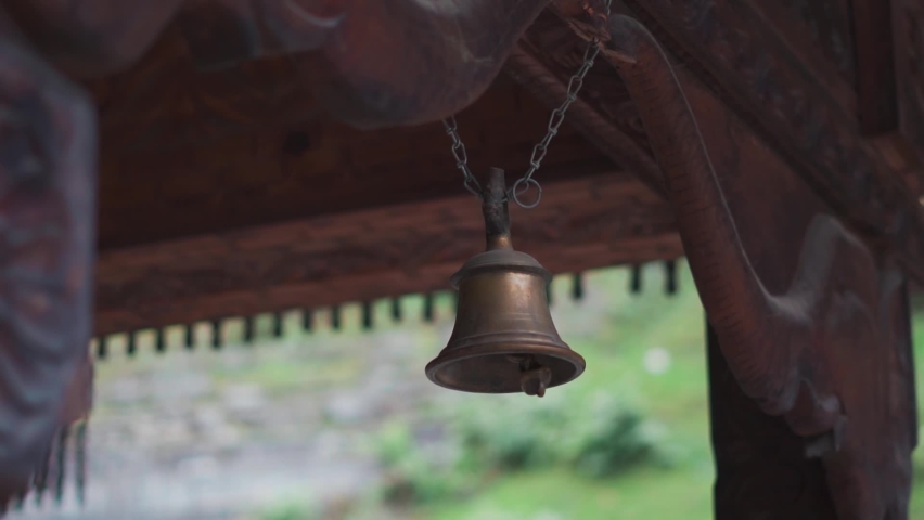 Closeup shot of brass or copper bell hanging from a chain at Tripura Sundari temple in Naggar near Manali in Himachal Pradesh, India. Temple bell in the temple in India. Religious background.  | Shutterstock HD Video #1097496287