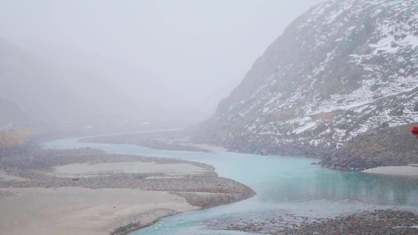 View of the river Chandra during the snow storm during the winter season at Sissu in Lahaul Spiti district, Himachal Pradesh. Blue coloured river during the snowfall in Himachal. Snowfall background.  | Shutterstock HD Video #1097500105