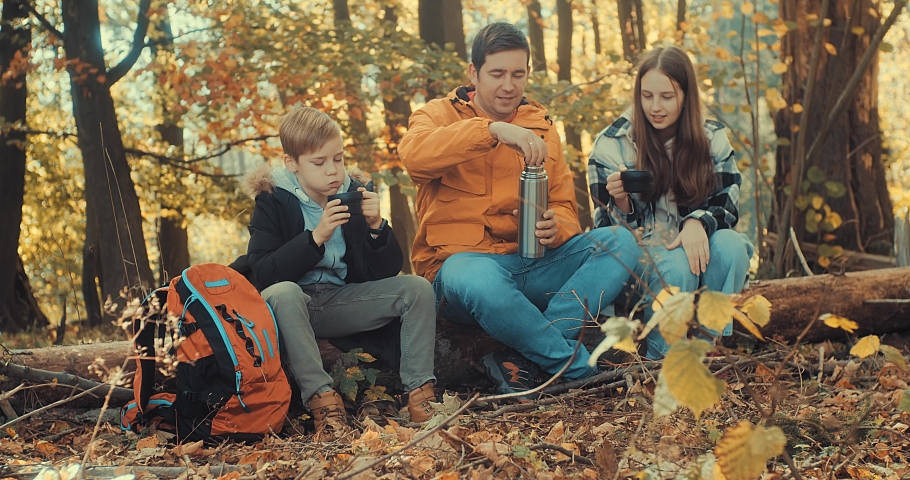 Autumn, Father and children bonding in forest nature, drinking hot tea a thermos in sunny autumn day, Fall wood. Contemporary Travel. Yellow, orange, ocher colour. Royalty-Free Stock Footage #1097500947