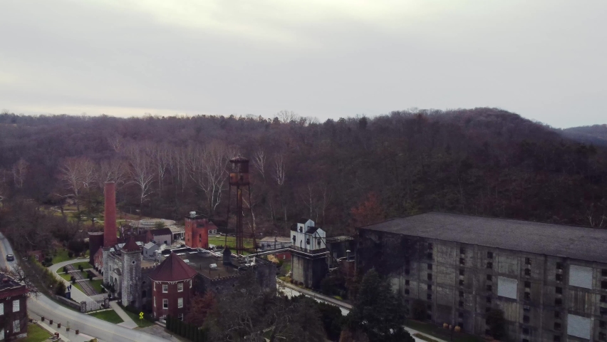 Descending to reveal bourbon distillery in rural Kentucky near the capital city of Frankfort. Old industrial buildings in a factory for producing American whiskey.