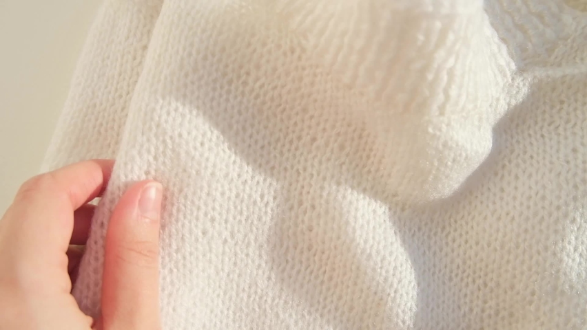 Close up hand stroking over the surface knitted soft wool cloth or warm fluffy sweater. Handcraft knitting woolen fabric. High quality FullHD footage with slow motion Royalty-Free Stock Footage #1097502275