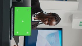 Vertical video: Medical specialists working at reception with greenscreen on laptop, using checkup form papers in health center. Isolated chroma key display with blank mockup template and copyspace on