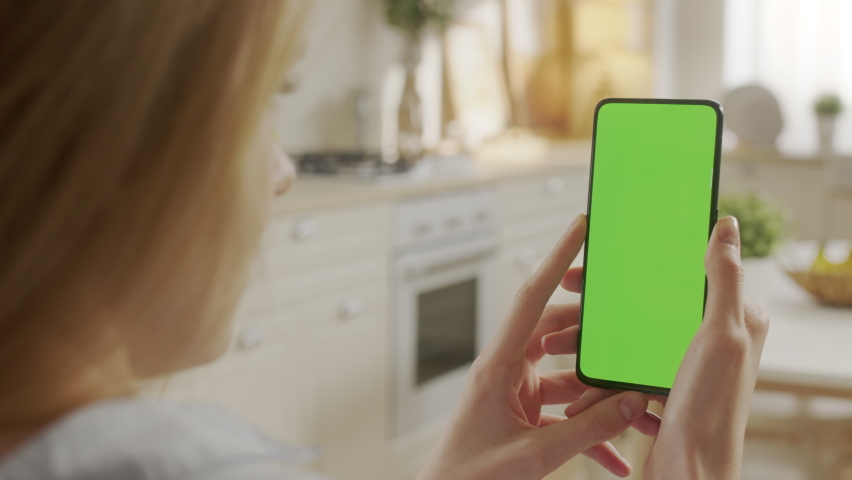 Handheld Camera: Back View of Woman at Phone with Green Screen for Copy Space. Chromakey Mock Up Without Tracking Markers. Close Up. Girl is Surfing Content With Touching Tapping on Center Screen Royalty-Free Stock Footage #1097509821