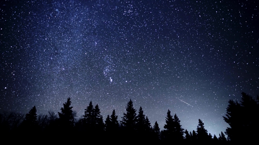 Time lapse of the Geminid meteor shower with more than 20 meteors and includes the Milky Way and Perseus star cluster. The foreground is a silhouettes pine and spruce forest.
