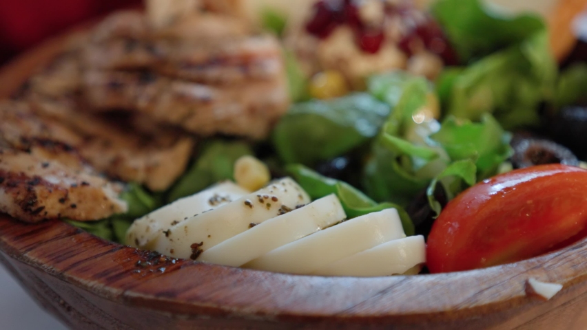 Person Eating Slices Of Boiled Egg On Grilled Chicken And Vegetable Salad On A Wooden Bowl With A Fork. - close up