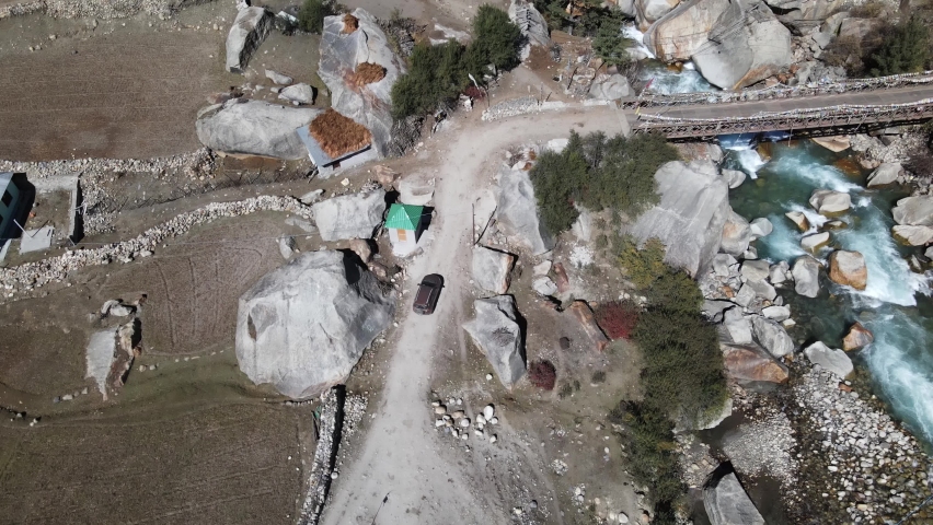 Aerial top down of a 4x4 car crossing a stone bridge in raksham village near chitkul town | Shutterstock HD Video #1097512559