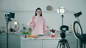 Young lady is getting filmed while cooking in the studio kitchen