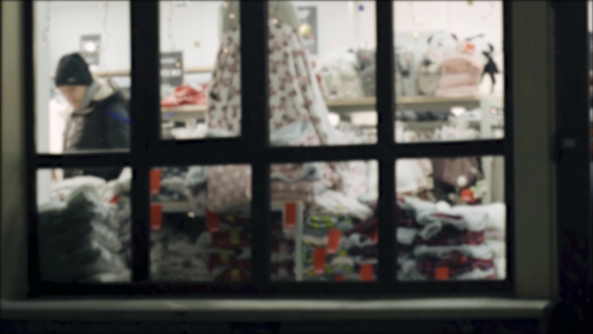 Background blurred image of a shop window in winter. A customer walks inside the store. | Shutterstock HD Video #1097516939