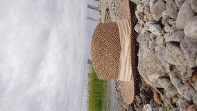 Man is coming and picking hat on beach in summer, close up view vertical