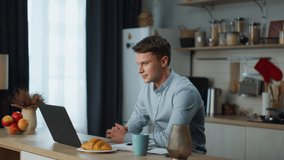 Young worker passing online interview using webcam on laptop sitting at kitchen table. Attractive man have video conversation with coworkers at home. Positive guy working with modern technologies. 