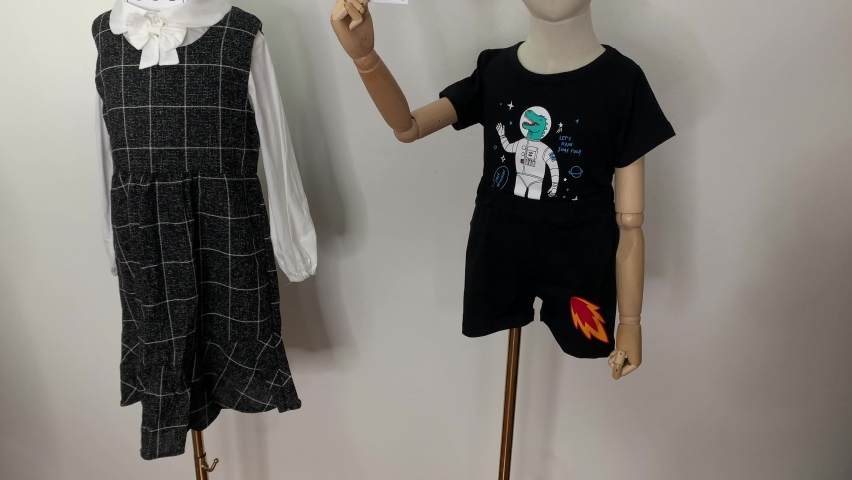 Child mannequin wear shirt, pants and dress on gold pole holding number card with white wall background | Shutterstock HD Video #1097527321