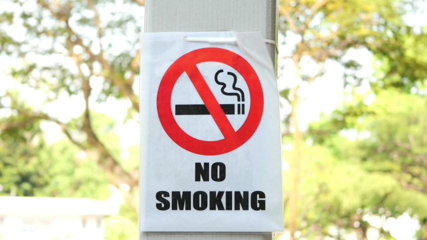 No smoke sign on a tree at public park.