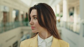 Portrait of the beautiful caucasian woman standing at shopping mall. Female customer looking at the camera inside. Skin, face. Close up view of the attractive woman