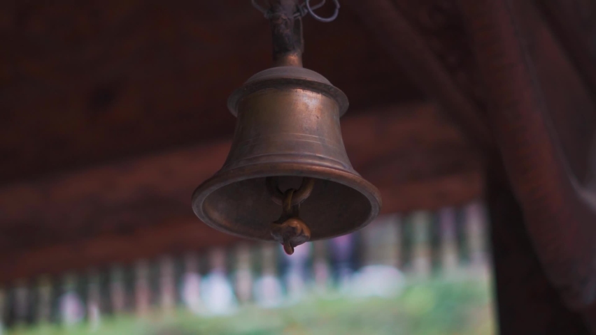 Closeup shot of brass or copper bell hanging from a chain at Tripura Sundari temple in Naggar near Manali in Himachal Pradesh, India. Temple bell in the temple in India. Religious background.  | Shutterstock HD Video #1097533049