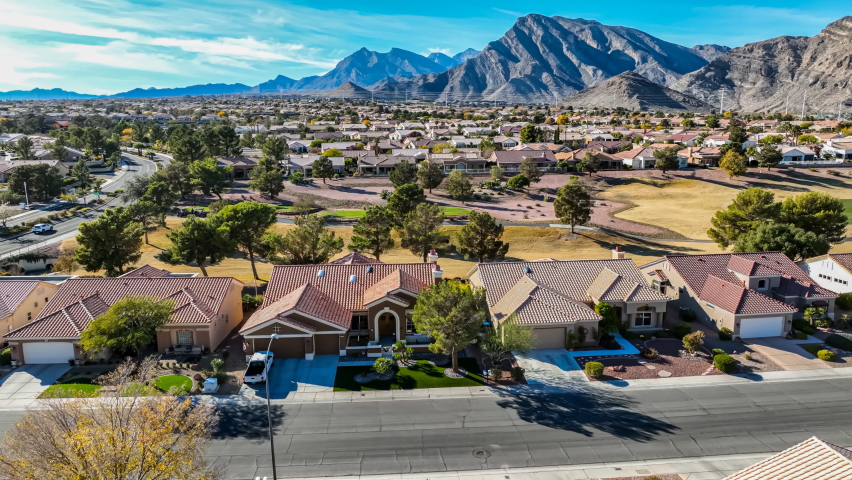 Aerial view of a southwestern suburban neighborhood with red tile rooftops, rising to reveal a scenic mountain landscape in the background | Shutterstock HD Video #1097537179