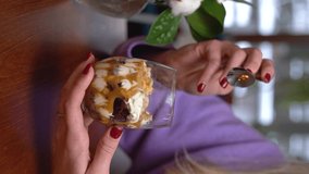 A woman eats a trifle dessert in a restaurant. Video for the vertical story