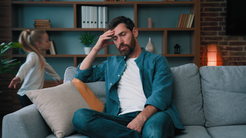 Irritated depressed caucasian man sad tired father feel stress headache due annoying active little child naughty girl disturb male parent babysitter. Noisy disobedient kid running at home bad behavior | Shutterstock HD Video #1097538257