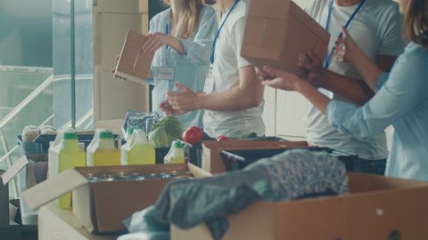 Charity, Donation, and Volunteering Concept - Group of Happy Smiling Volunteers Sorting Humanitarian Aid at Distribution or Refugee Assistance Center. Volunteer Warehouse, videoclip de stoc