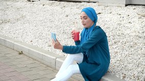 Arab female and technologies concept.. Young muslim woman talking on video call outdoors