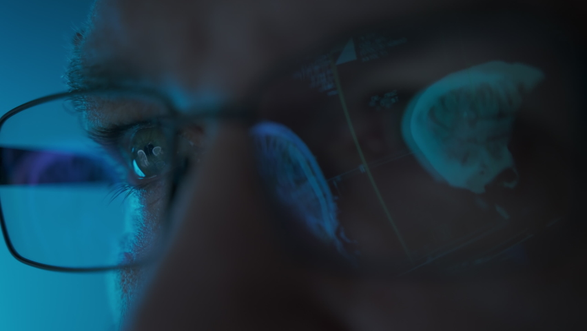 Male doctor eyes in eyeglasses late at night looking in front of MRI data on laptop. Macro shot Royalty-Free Stock Footage #1097546829
