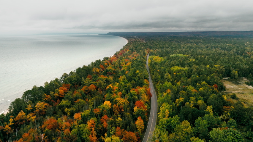 Aerial shot of a road running parallel to Lake superior in full fall color