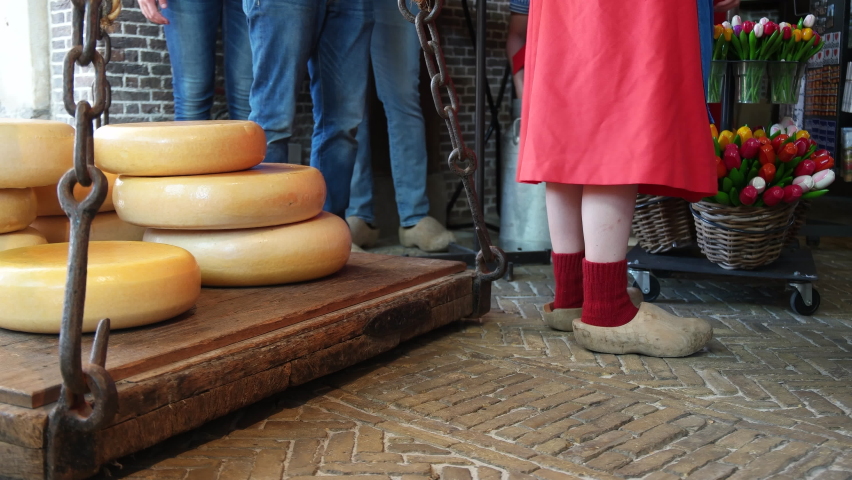 Dutch People At The De Goudse Waag Museum And Market In Gouda, Netherlands With Gouda Cheeses And Tulips In Display. medium shot