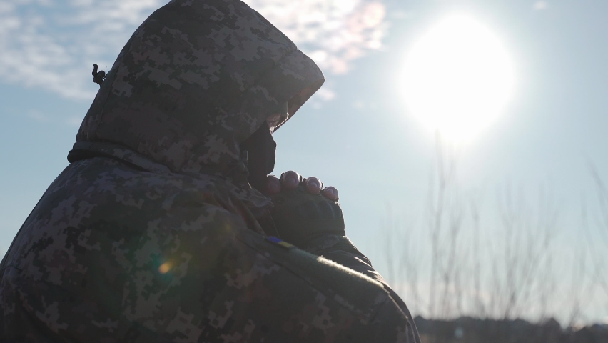 Ukrainian military man warms his hands with his breath on a cold winter morning. the officer at the post is warming up. war in winter winter military uniform. military service at sub-zero temperatures | Shutterstock HD Video #1097563229