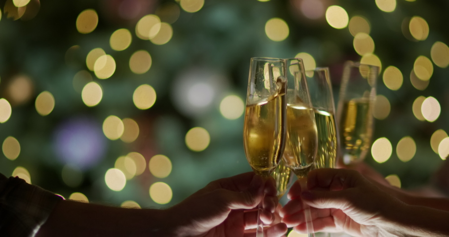 A group of friends clink glasses against the bokeh of a Christmas tree | Shutterstock HD Video #1097563761