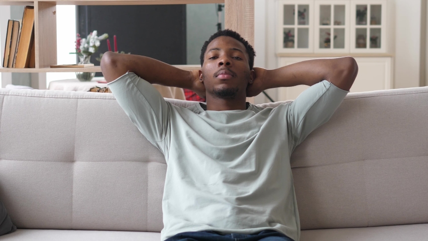 Young, relaxed African-American men is resting on the couch with her eyes closed after a hard day's work. The concept of rest and tranquility. Royalty-Free Stock Footage #1097566431