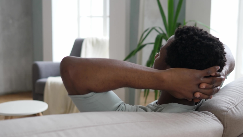 Young, relaxed African-American men is resting on the couch with her eyes closed after a hard day's work. The concept of rest and tranquility. Royalty-Free Stock Footage #1097566433