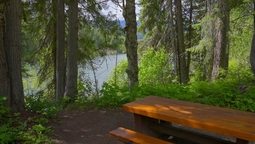 Establishing shot of Picnic Table in Park with mountain river background in slow motion at summer day in Vancouver, Canada, North America. Day time on September 2022. Still camera.
