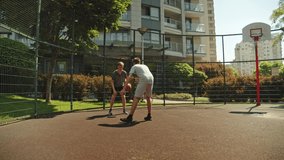 People playing street basketball during a warm summer day. Two teens playing a basketball match on an outdoors court during a sunny summer day.  Attack and defence, no shot.
