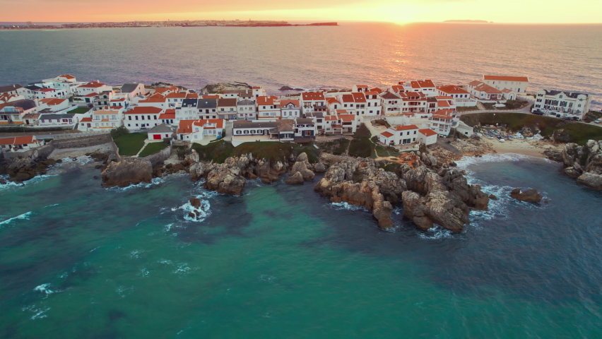 Aerial view of Baleal peninsula near Peniche town on the west coast of Portugal at sunset. Drone footage of the rocky Baleal island in Portugal. Portuguese travel and surfing destination. Orbit shot