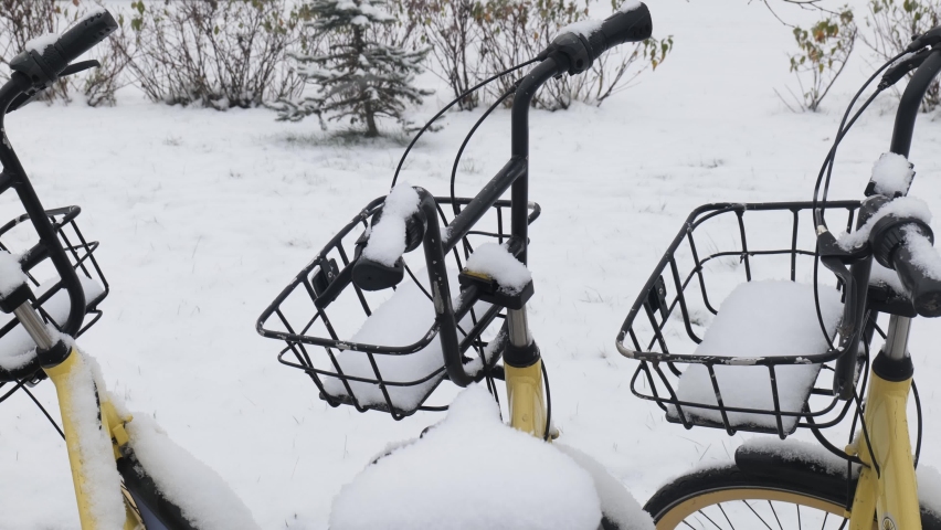 Bicycles covered with snow stand during a snowfall