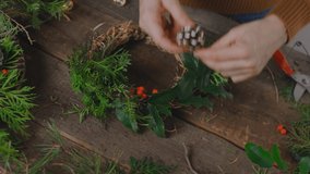 DIY Christmas home interior decoration. Female hands decorating Christmas wreath with pine cone. - Powered by Shutterstock - Get 15% off with code: PIKWIZARD15