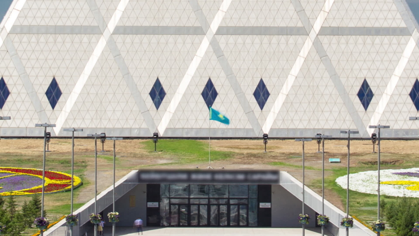 Exterior of the Palace of Peace and Reconciliation building timelapse with park and fountains near by. Nur-Sultan city, Kazakhstan.