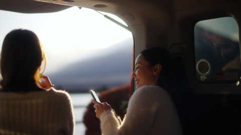 Happy Asian woman friends relax and enjoy outdoor lifestyle using mobile phone with internet while driving car travel Kawaguchi lake and Mt Fuji covered in snow on autumn road trip holiday vacation. Video stock