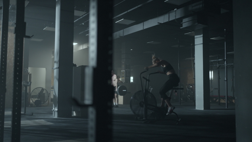 athletic woman is exercicing with stationary bike in gym, losing weight and keeping fit