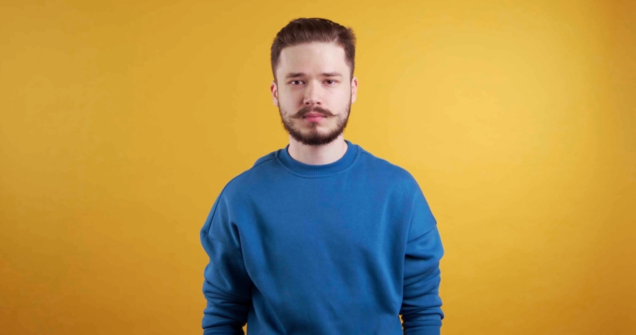 Scared young man dodging something on yellow background | Shutterstock HD Video #1097599627