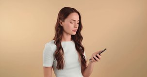 Unhappy young woman with mobile phone got bad news. Beige background