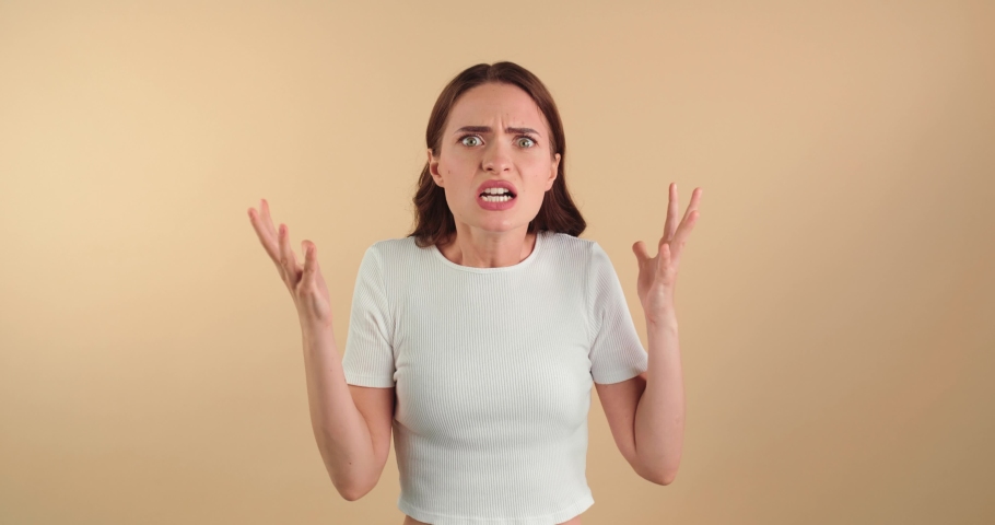 Indignant young woman resenting on beige background